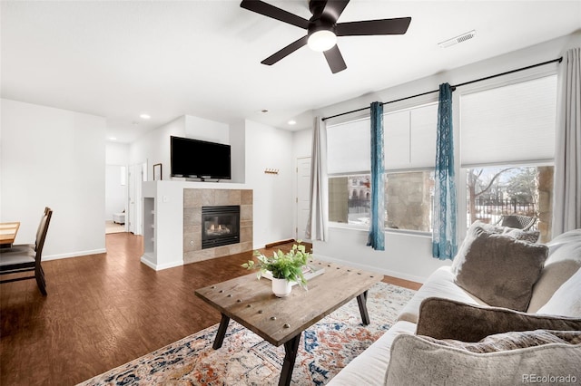 living room featuring a tile fireplace, hardwood / wood-style flooring, and ceiling fan