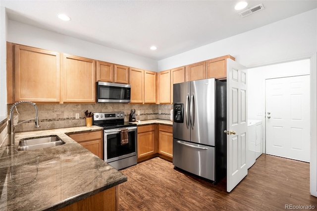 kitchen with sink, stainless steel appliances, washing machine and dryer, and dark wood-type flooring