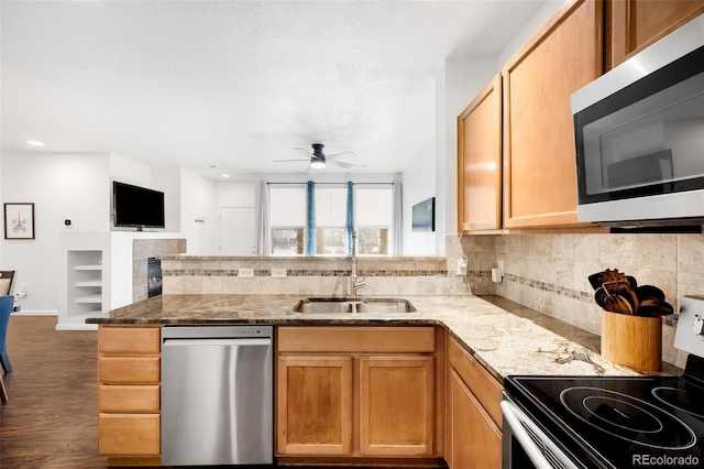 kitchen with appliances with stainless steel finishes, sink, kitchen peninsula, dark hardwood / wood-style flooring, and ceiling fan