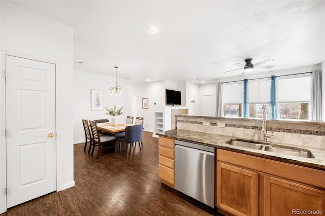 kitchen with stone counters, hanging light fixtures, stainless steel dishwasher, sink, and dark hardwood / wood-style flooring