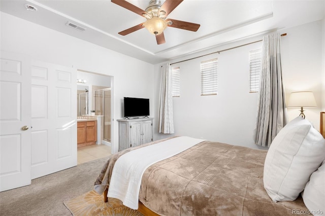 bedroom with ceiling fan, ensuite bathroom, and light carpet