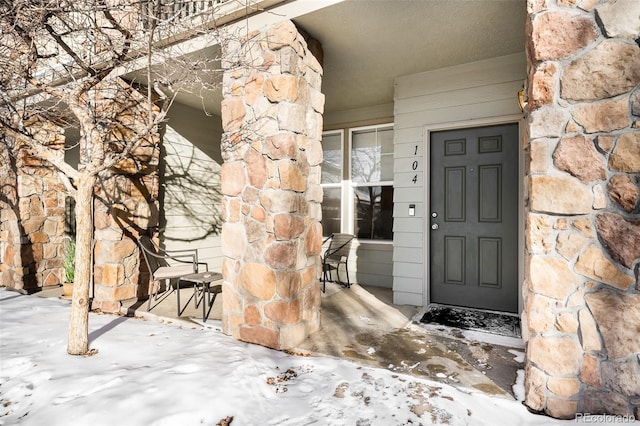 property entrance with a porch and stone siding