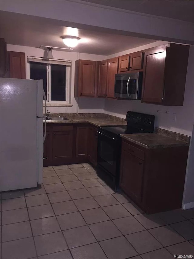 kitchen with white refrigerator, sink, light tile patterned floors, and electric range