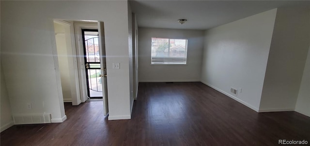 spare room featuring a healthy amount of sunlight and dark wood-type flooring