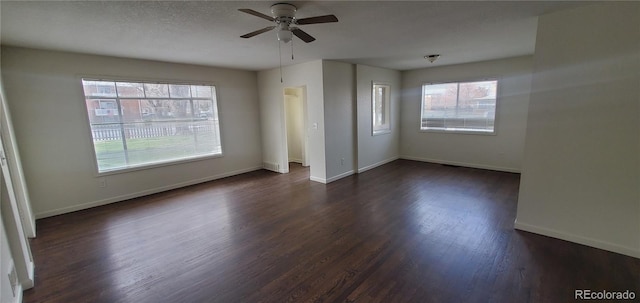 unfurnished room featuring ceiling fan, dark hardwood / wood-style floors, a textured ceiling, and a healthy amount of sunlight