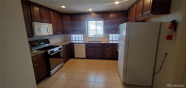 kitchen with light tile patterned floors, white appliances, sink, and stone counters