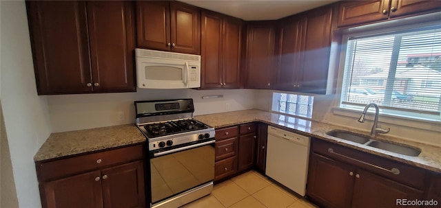 kitchen with white appliances, sink, light stone counters, and plenty of natural light