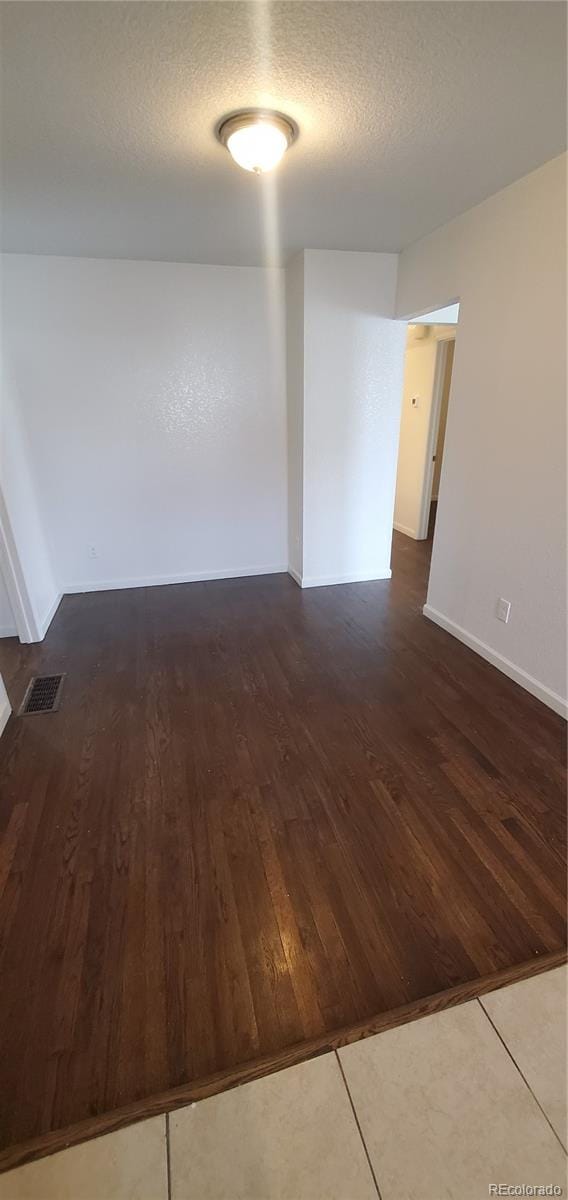 spare room featuring dark hardwood / wood-style flooring and a textured ceiling