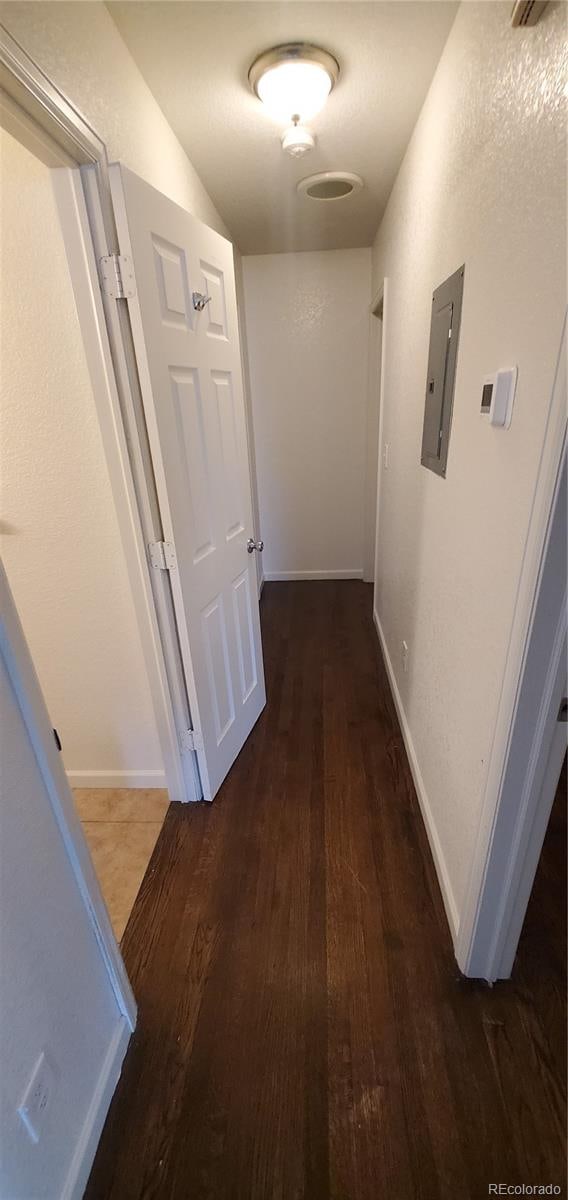 corridor with electric panel and dark hardwood / wood-style flooring