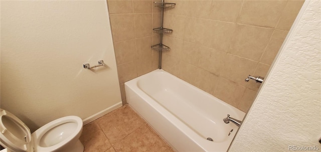 bathroom with tiled shower / bath, tile patterned flooring, and toilet