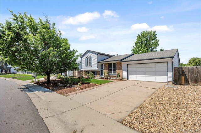 1153 S Biscay St, Aurora, CO 80017 - tri-level home with a garage, driveway, brick siding, and roof with shingles