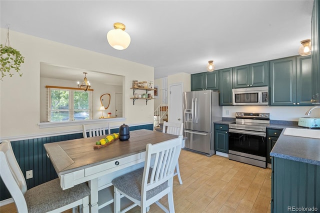1153 S Biscay St, Aurora, CO 80017 - kitchen featuring appliances with stainless steel finishes, a sink, dark countertops, light wood-type flooring, and a chandelier