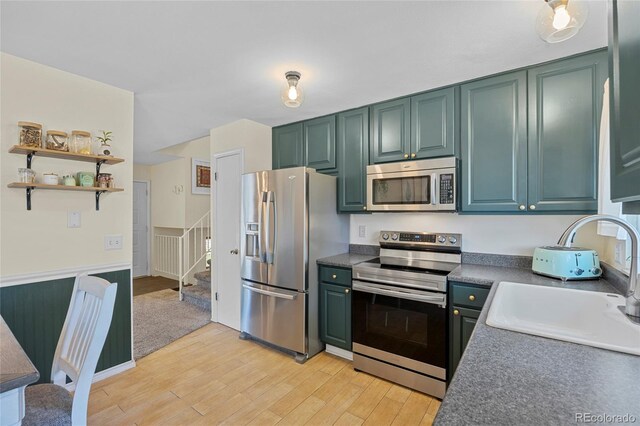 1153 S Biscay St, Aurora, CO 80017 - kitchen featuring appliances with stainless steel finishes, a sink, light wood-style floors, green cabinets, and dark countertops