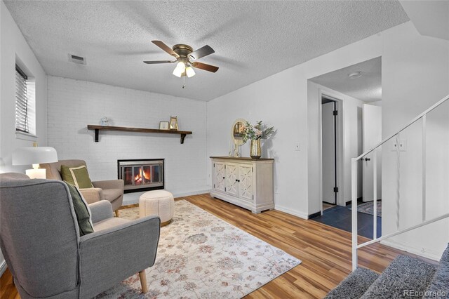 1153 S Biscay St, Aurora, CO 80017 - living room featuring wood finished floors, a ceiling fan, a fireplace, a textured ceiling, and baseboards