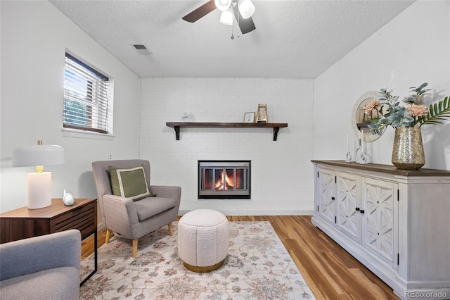 1153 S Biscay St, Aurora, CO 80017 - sitting room with wood finished floors, a textured ceiling, a fireplace, and ceiling fan