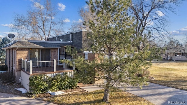 view of front of house featuring a shingled roof, a front lawn, mansard roof, and brick siding