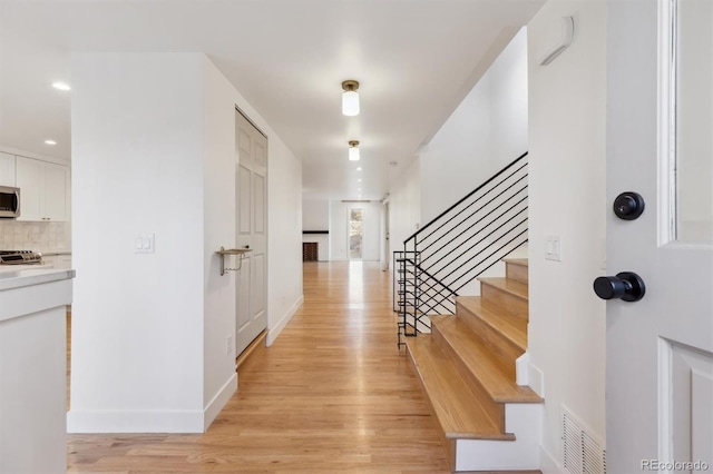 foyer featuring light wood finished floors, baseboards, visible vents, stairway, and recessed lighting