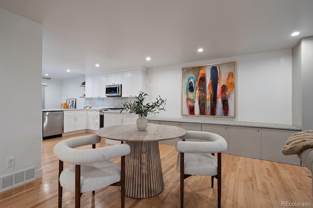 dining room with light wood finished floors, visible vents, and recessed lighting