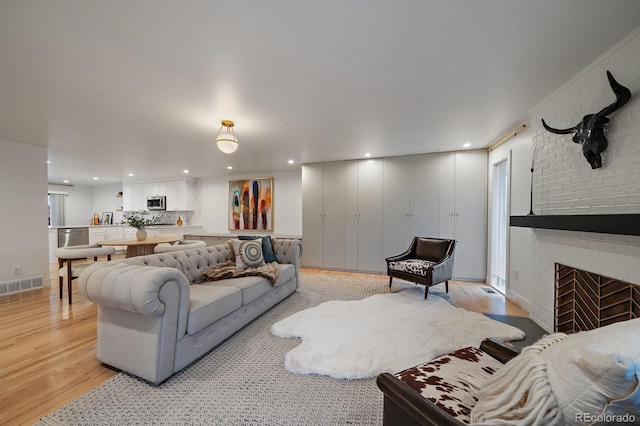 living room with light wood-style floors, recessed lighting, visible vents, and a fireplace