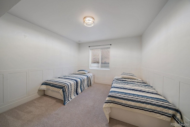 bedroom with a wainscoted wall, a decorative wall, and carpet flooring