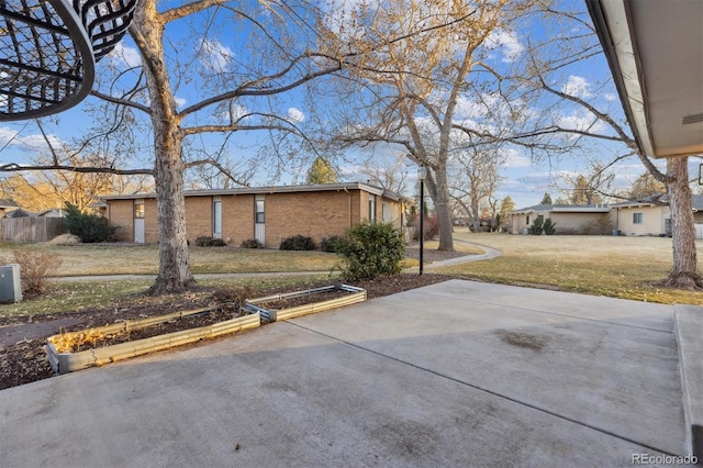 view of property exterior with a yard, brick siding, and fence