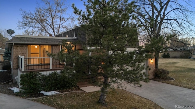 view of front of property with driveway, a garage, a shingled roof, covered porch, and brick siding