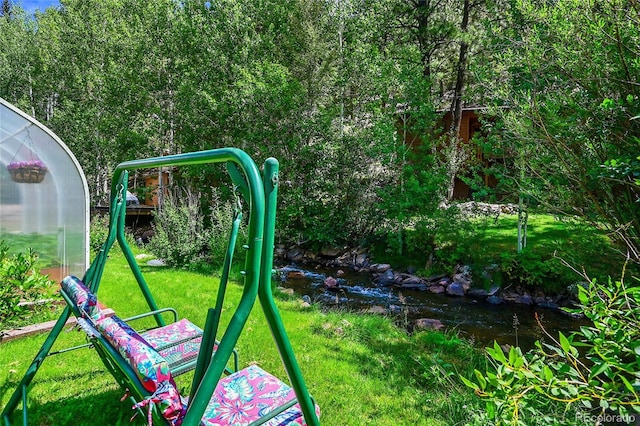 view of play area featuring a lawn and a water view