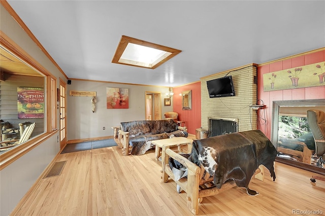 living room with a fireplace, brick wall, a skylight, and light wood-type flooring