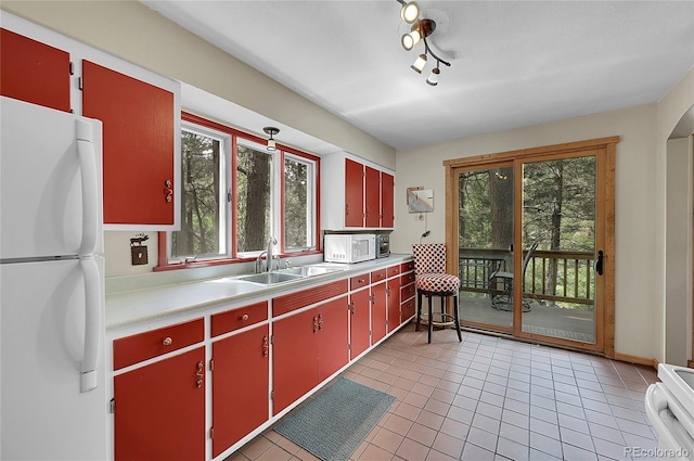 kitchen featuring a wealth of natural light, sink, white appliances, and light tile patterned floors