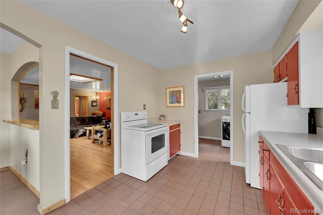 kitchen featuring white range with electric stovetop, washer / dryer, tile patterned floors, sink, and rail lighting