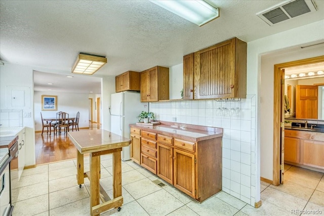 38 D Rd, Silverthorne, CO 80498 - kitchen featuring freestanding refrigerator, brown cabinetry, tile counters, light tile patterned flooring, and a textured ceiling