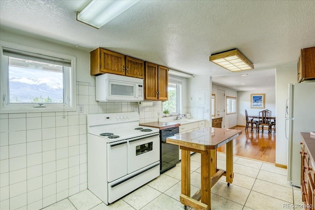 38 D Rd, Silverthorne, CO 80498 - kitchen featuring white appliances, brown cabinetry, a textured ceiling, light tile patterned flooring, and a sink