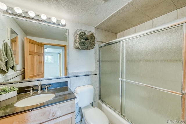 38 D Rd, Silverthorne, CO 80498 - full bathroom with tile walls, vanity, toilet, bath / shower combo with glass door, and a textured ceiling