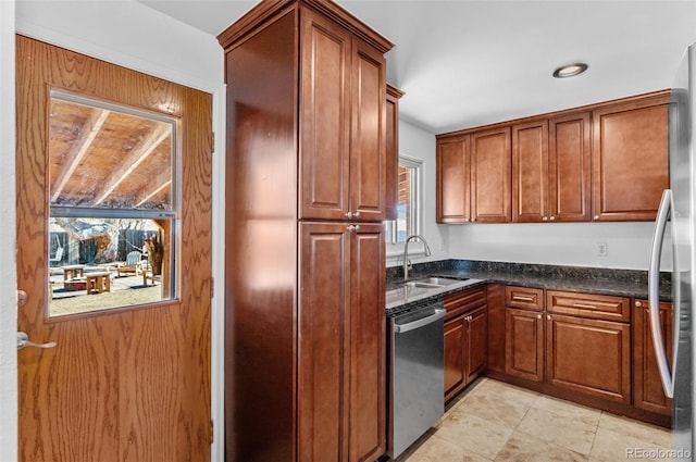 kitchen with light tile patterned flooring, appliances with stainless steel finishes, sink, and dark stone countertops