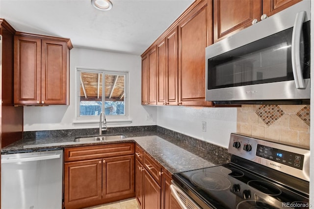 kitchen with dark stone countertops, sink, backsplash, and appliances with stainless steel finishes