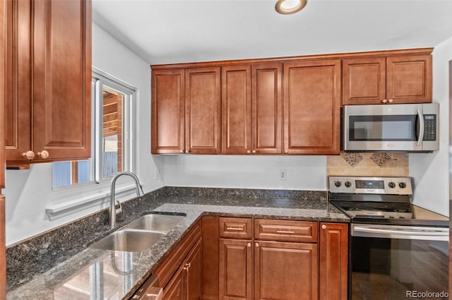 kitchen with appliances with stainless steel finishes, sink, and dark stone countertops