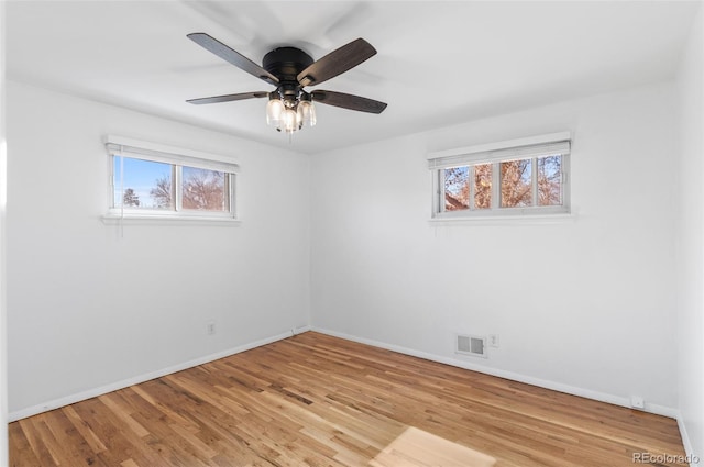 spare room featuring ceiling fan, a healthy amount of sunlight, and light wood-type flooring