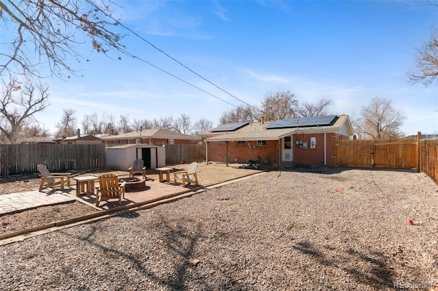 rear view of property with solar panels, a patio, and an outdoor fire pit