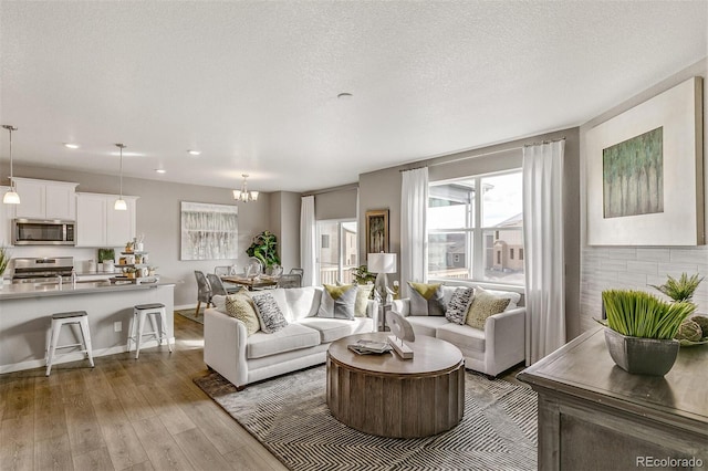 living room featuring a notable chandelier, a textured ceiling, and light hardwood / wood-style flooring