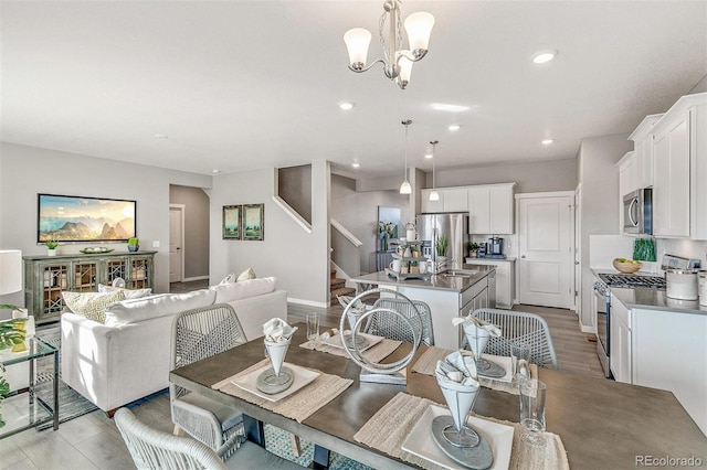 dining space featuring an inviting chandelier, sink, and light hardwood / wood-style floors