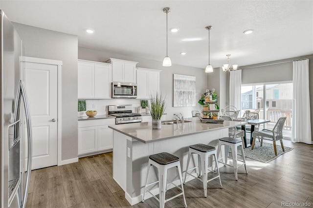 kitchen featuring white cabinetry, stainless steel appliances, sink, and pendant lighting