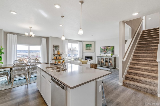 kitchen featuring pendant lighting, sink, white cabinetry, a kitchen island with sink, and stainless steel dishwasher