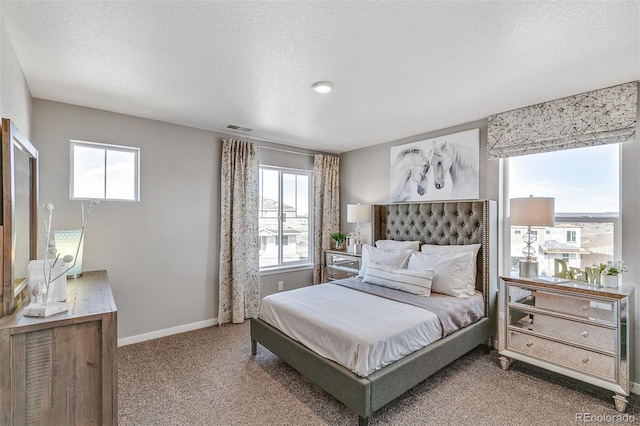 bedroom featuring multiple windows, a textured ceiling, and carpet