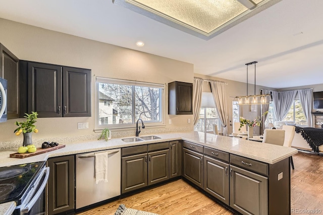 kitchen featuring pendant lighting, sink, appliances with stainless steel finishes, light hardwood / wood-style floors, and kitchen peninsula