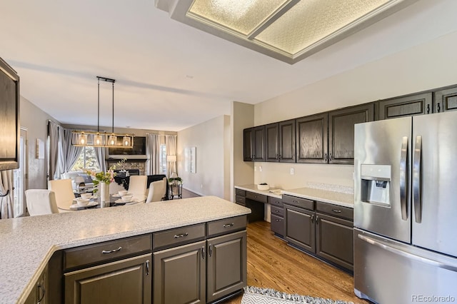 kitchen featuring pendant lighting, light hardwood / wood-style flooring, dark brown cabinets, stainless steel refrigerator with ice dispenser, and built in desk