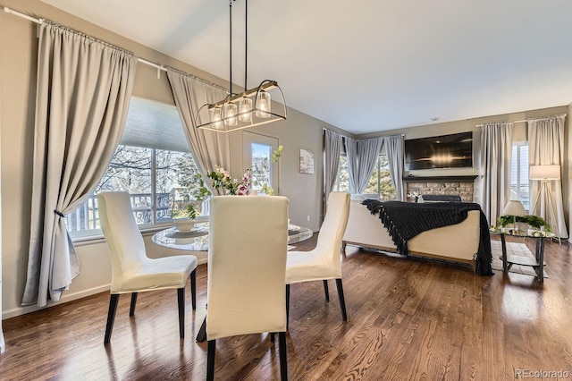 dining room with hardwood / wood-style floors and a stone fireplace