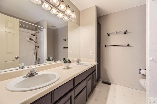 bathroom with vanity, tiled shower, and toilet