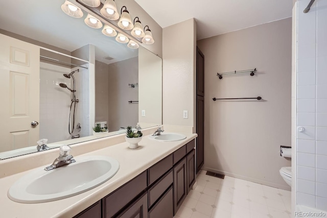 bathroom with vanity, toilet, and tiled shower