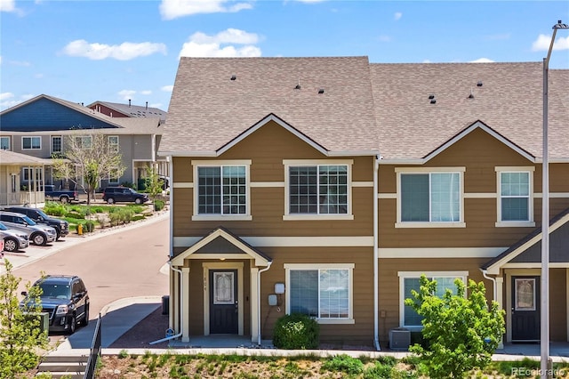 multi unit property featuring roof with shingles and central AC unit