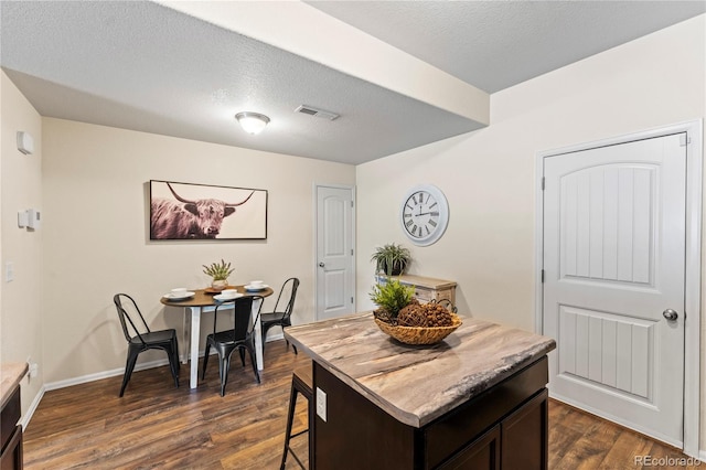 dining area with dark wood-style flooring, a textured ceiling, and baseboards